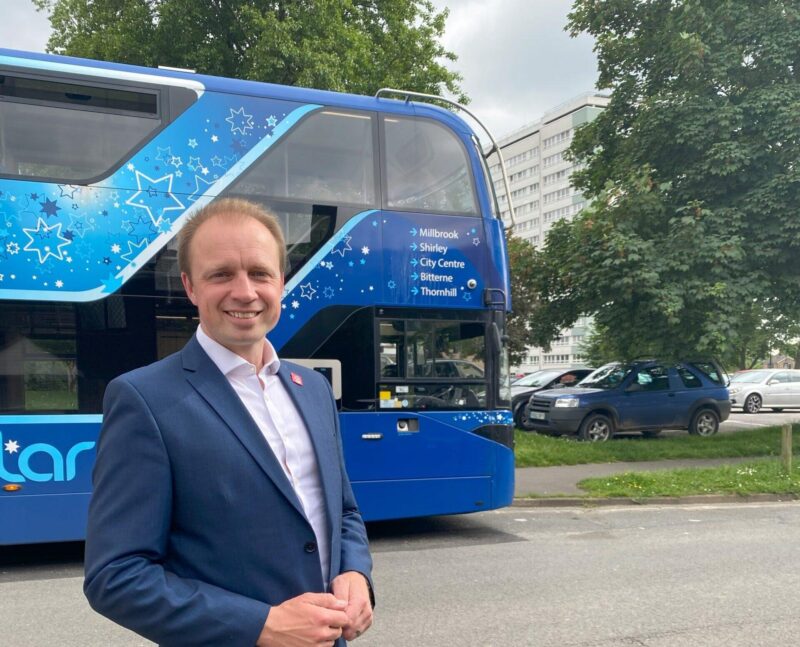 Darren Paffey MP stood in front of a BlueStar Bus. 